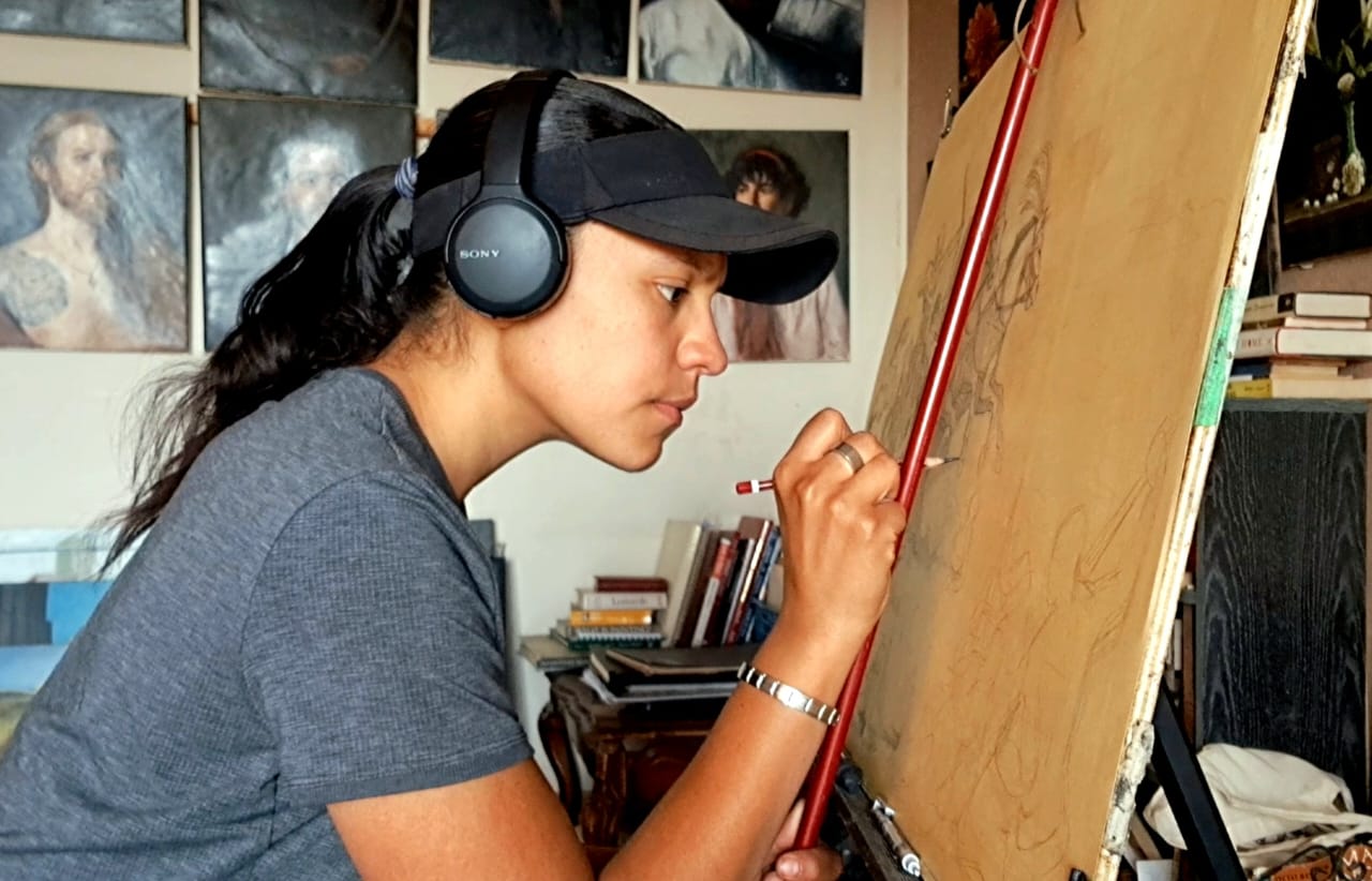 Aya Aziz working at her easel in the studio.